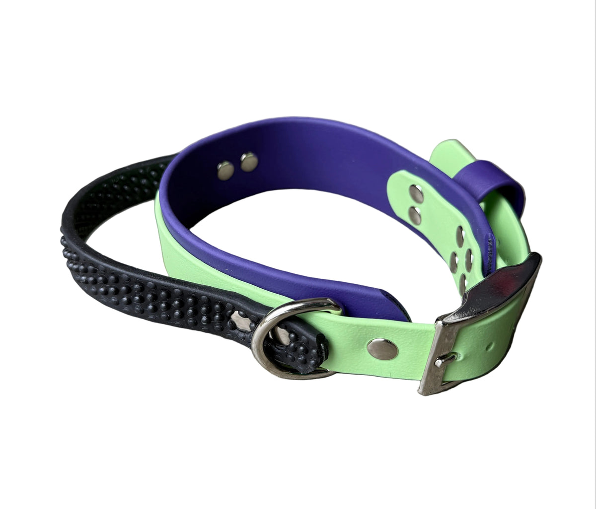 A two-tone dog collar made of purple and lime green leather, featuring a black rubber spiked guard strap and silver-tone hardware,