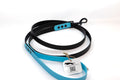 A six foot black biothane dog leash with a light blue accents, shown coiled on a white background with a product tag attached.